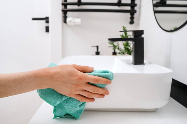 istock Woman cleaning white washbasin with a cloth 1486766139