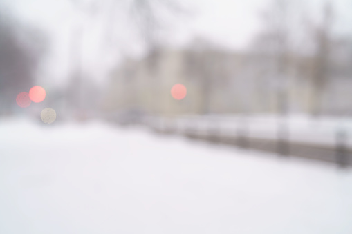 snowfall in town with blurred moving cars on background, blurred backdrop