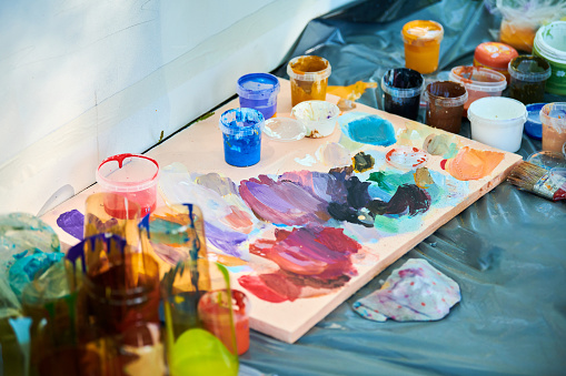 Art artist colorful palette with paint jars at outdoor art painting festival, paintings art picture process. Colorful palette for artist painting, color selection for image painting