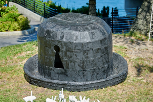 Art installation big black hat with keyhole on green grass and white artificial rabbits around lawn