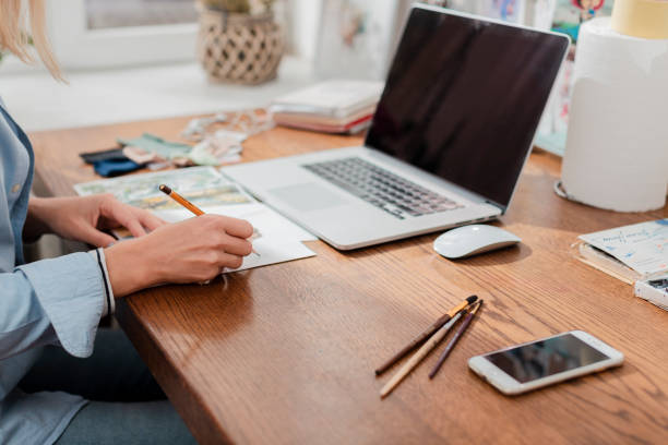 A business woman writing a script for her business plan and laptop with smartphone on the table.