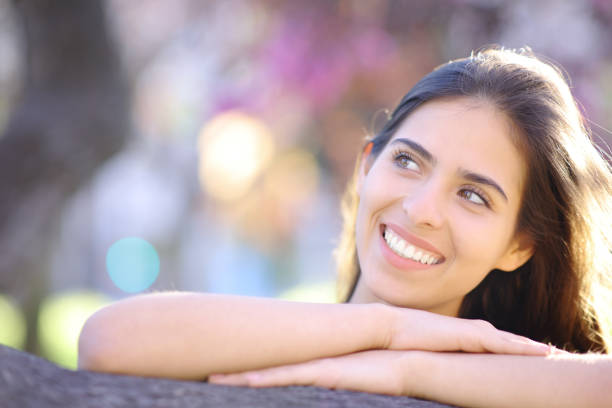 Attractive young blonde woman sitting and smiling on the grass outside