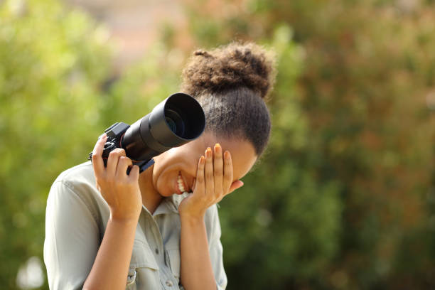 embarrassed photographer laughing and hiding face holding camera - shy women camera paparazzi photographer imagens e fotografias de stock