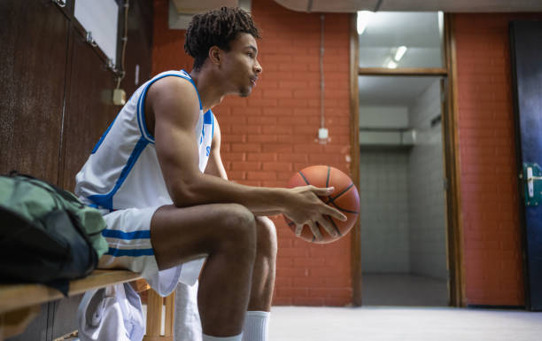 Male Basketball Star With Basketball In Locker Room Basketball player concentrates in the locker room and thinks about the game. Team sport and healthy lifestyle concept. athlete fails stock pictures, royalty-free photos & images