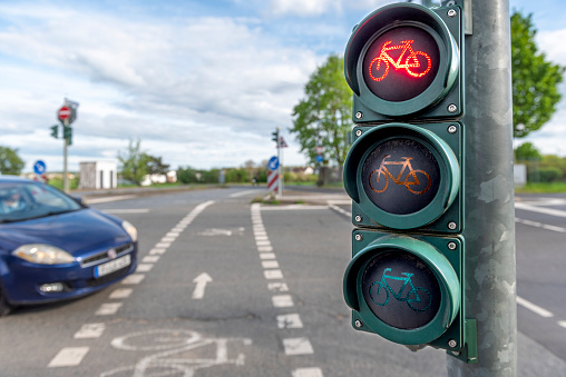 Closeup of a bicycle traffic light at red phase with a passing blurred car