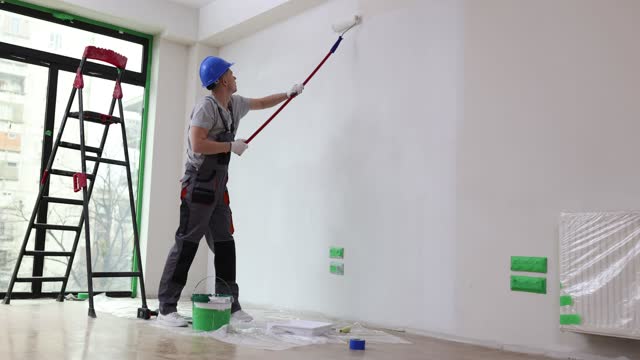 House painter paints wall white with roller