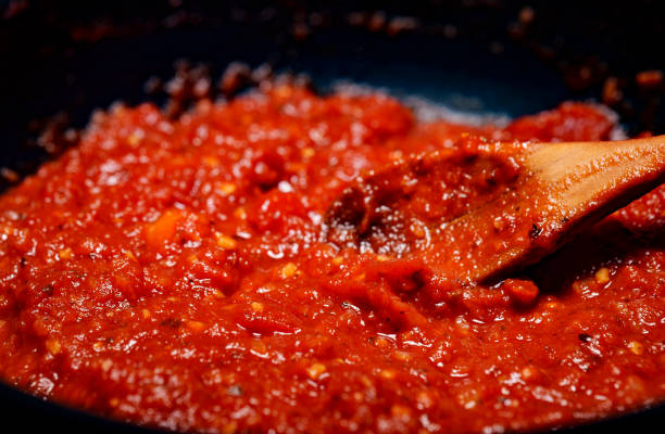 istock Stirring with a spoon of tomato pizza sauce. 1486781310