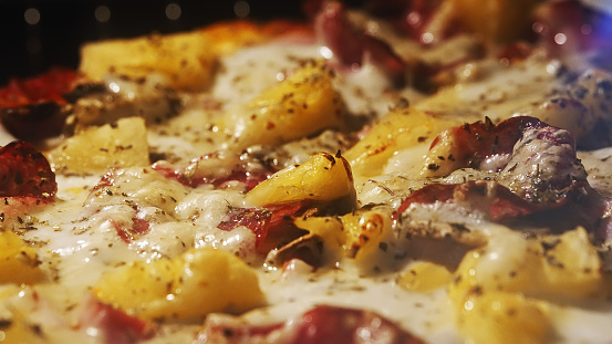 Pizza with pineapple and pepperoni in the oven.