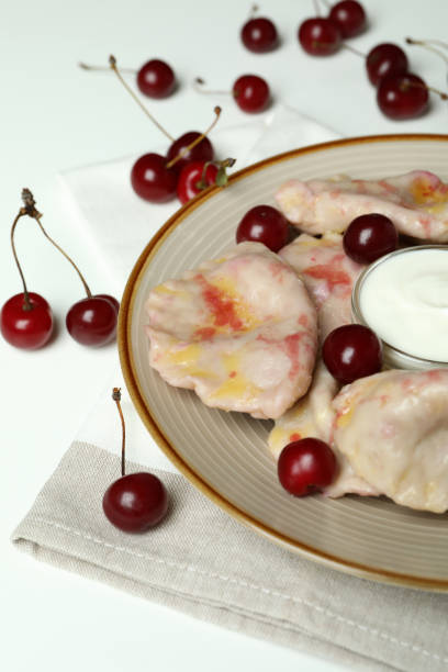 istock Plate with pierogi with cherry on kitchen towel on white background 1486781516