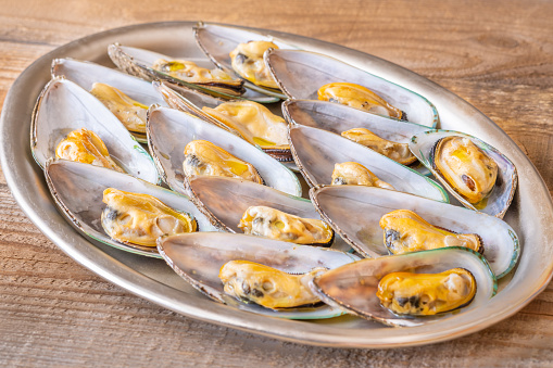 Tray of baked half shell mussels on wooden background