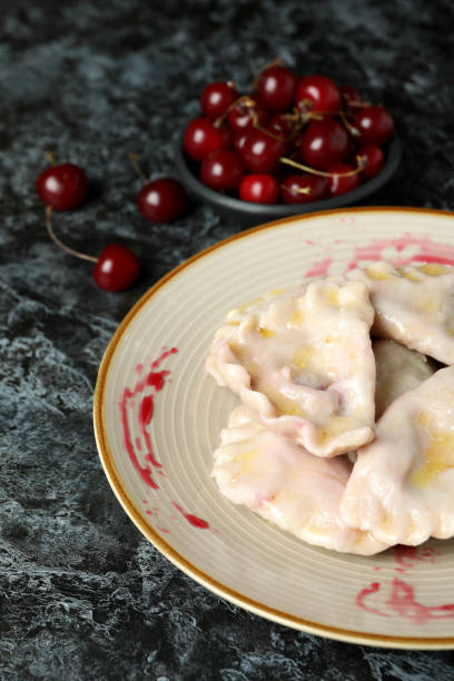 istock Plate with pierogi with cherry on black smokey background 1486781710