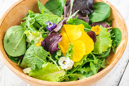 Bowl of fresh green salad with flowers