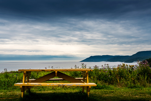 A picnic wooden table with gorgeous view at ocean with sun shining through the clouds in Iceland. Place for rest travel concept.