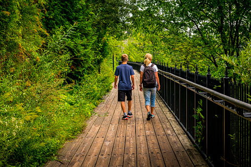 mother and her son walking along a wooden footbridge in forest