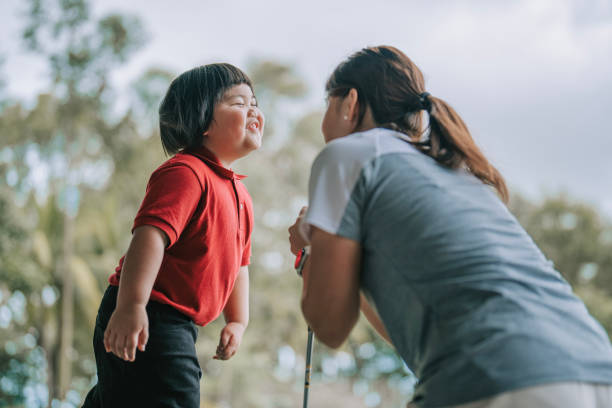 playful asian chinese boy making face to instructor in golf practicing class at driving range - golf child sport humor imagens e fotografias de stock
