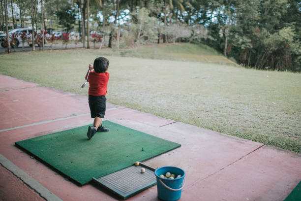 азиатский китайский мальчик практикует удар в гольф на тренировочном поле - golf driving range practicing bucket стоковые фото и изображения
