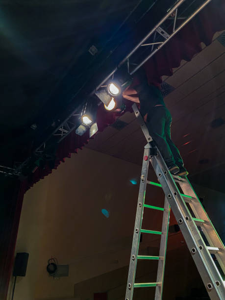 istock Young male light technician standing on a ladder installing spotlights 1486797923