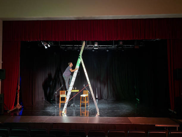 istock Young male light technician standing on a ladder installing spotlights 1486798777
