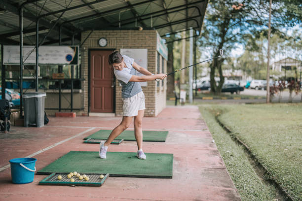 азиатская китаянка-гольфистка практикует удар в гольф на тренировочном поле - golf driving range practicing bucket стоковые фото и изображения