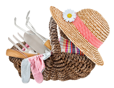 Garden tools and straw hat in a basket isolated on white background