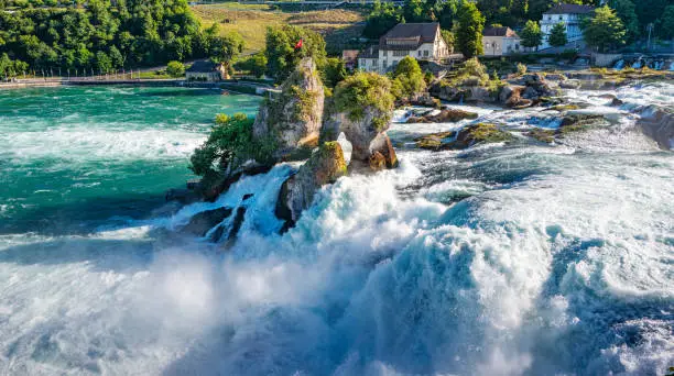 Rhine River cascading down Europe's largest waterfall, The Rhine Falls. The Rhine Falls runs between Zurich and Schaffhausen, Switzerland.