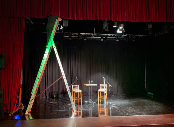 istock Young male light technician standing on a ladder installing spotlights 1486809574