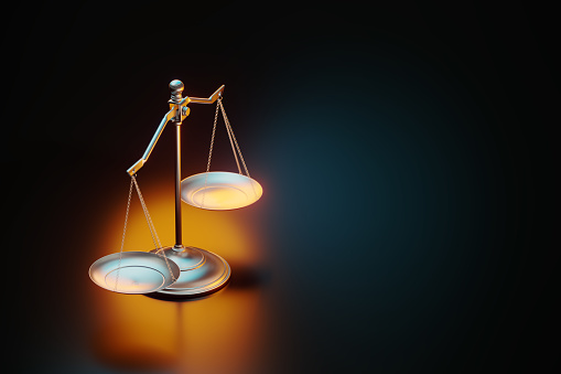 Brass scale illuminated by yellow and blue lights on black background. Horizontal composition with copy space. Justice concept.