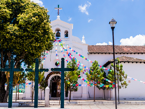 Iconic San Lorenzo church with colorful prayer flags and three christian crosses into its parvis , Zinacantan, Chiapas, Mexico