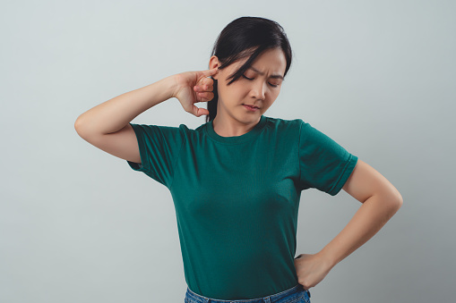 Woman itching putting a finger into her ear standing isolated on background.