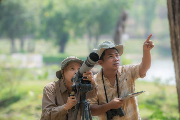 Two Retired Male Friends On Walking Holiday Looking Through Binoculars