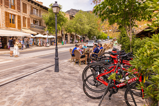 Valldemosa, Spain -April 22, 2023: Cyclist team sitting together in an outdoor cafeteria on the main street in the famous village Valldemosa. Valldemosa is known for being one of the most authentic and beautiful villages on the island of Mallorca, and it attracts visitors from all over the world throughout the year.