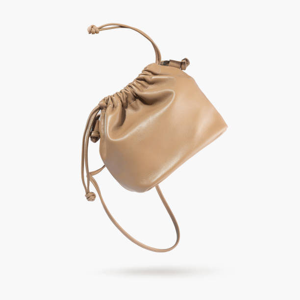 A brown female handbag with straps flying on a gray background. Minimalistic layout with bag. Advertising for ladies store, blog. Trendy women's accessories. Copy space. Objects for design, Mock up