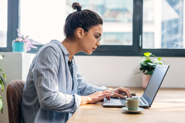 istock Beautiful attractive entrepreneur woman working with laptop while drinking coffee in the living room at home. 1486836635
