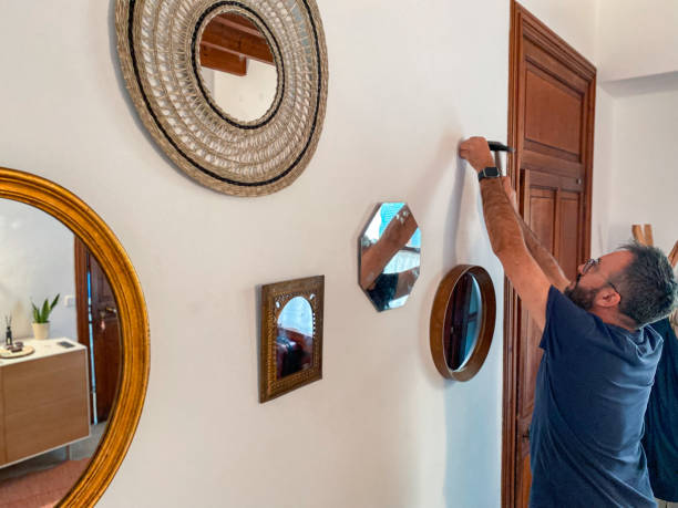 istock Man with a hammer hammering nails into the wall to hang mirrors 1486837317