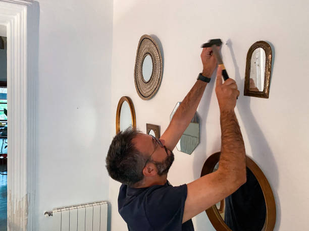 istock Man with a hammer hammering nails into the wall to hang mirrors 1486837456