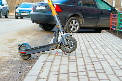 Voronezh, Russia - March 25, 2023: A scooter left incorrectly after a ride on the sidewalk. parking and traffic violations. part of the vehicle. close-up