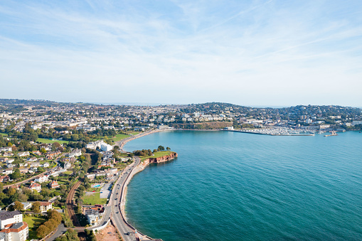 An aerial view looking over Torquay Sea Front in South Devon. Shot on a sunny day with blue ocean and the tide in.