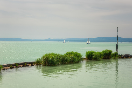 Scenic view of Lake Balaton in Hungary, summer landscape with green water, cozy settlement, yachts and sky, outdoor travel background