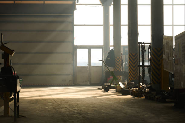 Empty workshop or hangar of industrial factory with concrete columns standing in row along huge machines and other equipment