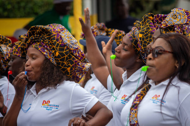 African women celebrate with song and dance wearing traditional wax print scarfs Maputo, Mozambique - May 01, 2023: African women celebrate with song and dance wearing traditional wax print scarfs mozambique woman stock pictures, royalty-free photos & images