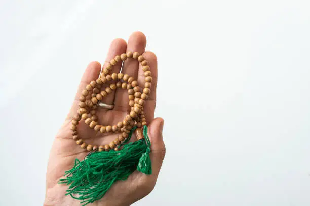 Hand holding tasbih isolated on white background, National Mantra Day concept image