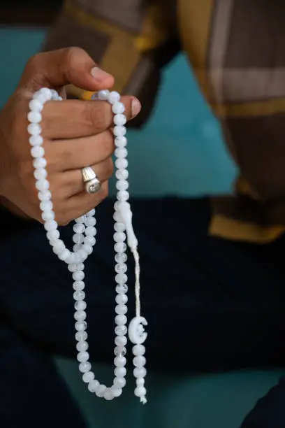 Muslim person praying with tasbih, National Mantra day concept image