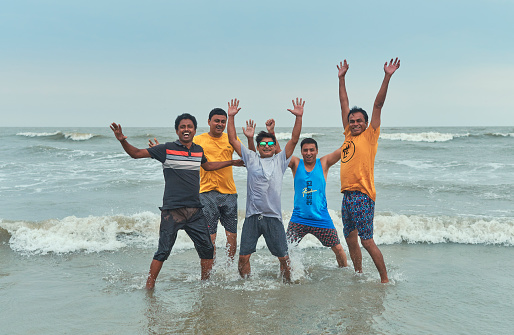 Mandarmani, 04-22-2023: group of friends having a blast while bathing in sea during a monsoon day.