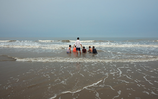 Mandarmani, 04-22-2023: group of friends having a blast while bathing in sea during a monsoon day. Photo taken on a monsoon day with overcast sky.