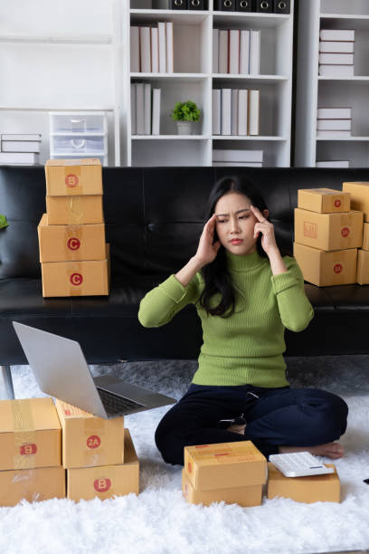 Young Asian business entrepreneur feeling stressed about her online business sells. Young Asian business entrepreneur feeling stressed about her online business sells. newspaper seller stock pictures, royalty-free photos & images