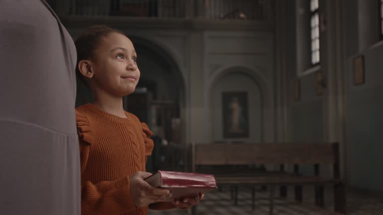 Pastor Giving Bible Book to Little Girl in Church