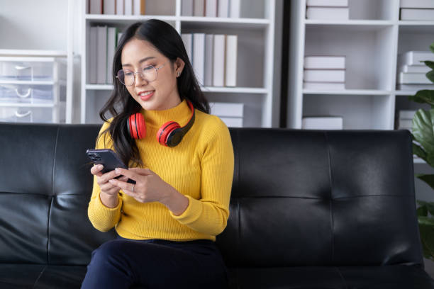 istock Young adorable Asian woman using smartphone in her free time while sitting on the sofa. 1486861814