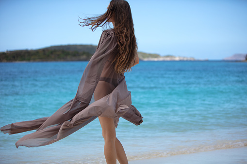 Attractive woman walking with beach cover up on a tropical beach, Scott Beach, St. John