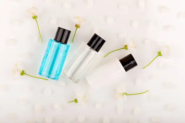 Photo of Three mini bottles of cosmetic products among the flowers