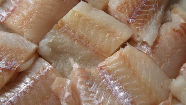 Raw fish fillet is spinning. Top view. Slices of fresh whitefish. Full frame. Sashimi rotation. Close up. Marine market. Video for sale. Cod, pollock loin steaks. Pangasius, tilapia pieces background.